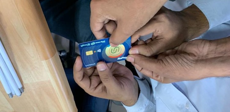 Two people holding Union Sparsh Card and a white cane on the desk